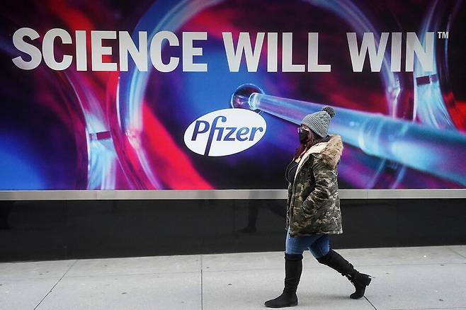 지난 7일 미국 뉴욕 맨해턴 거리의 화이자 백신 광고판 앞을 한 시민이 걸어가고 있다. 뉴욕/로이터 연합뉴스