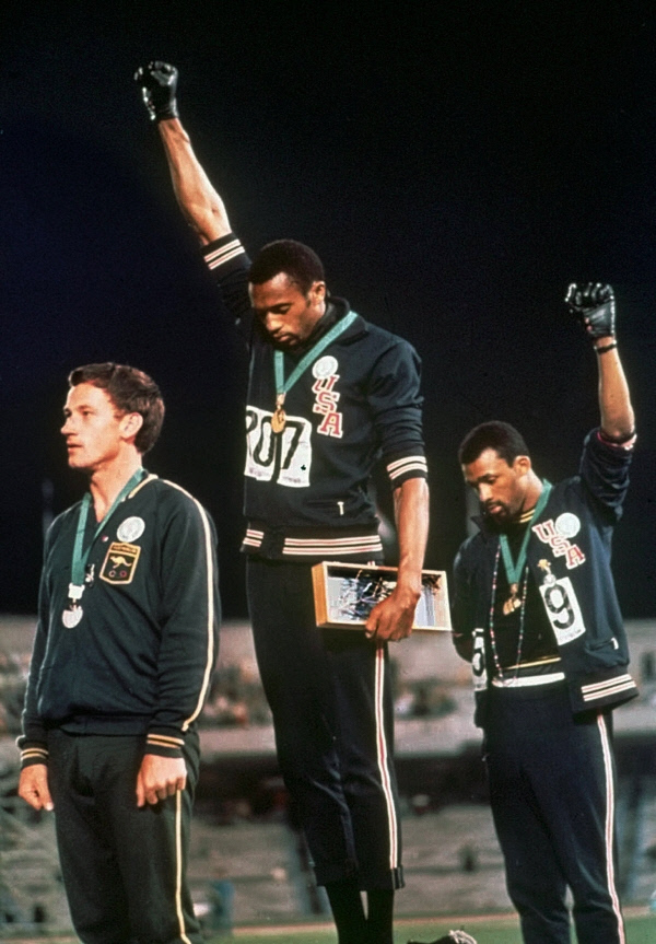 미국의 육상 단거리 선수인 토미 스미스(가운데)와 존 카를로스(오른쪽)가 1968 멕시코시티올림픽 육상 남자 200m 시상식에서 주먹을 쥔 손을 치켜들고 있다. AP뉴시스