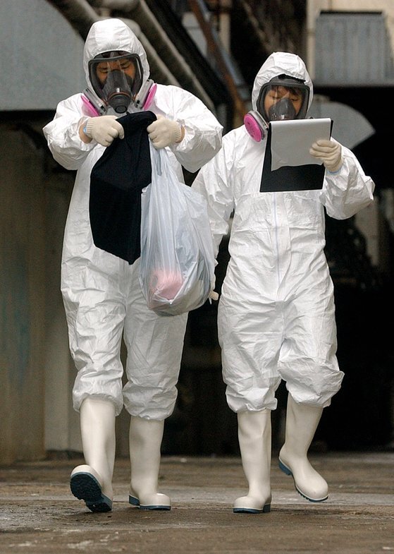 지난 2003년 4월 홍콩의 보건 당국 관계자들이 중증 급성 호흡기 증후군(SARS) 환자가 집단 발생한 아모이가든스에서 감염자의 소지품으로 보이는 물건들을 들고 나오고 있다. AP=연합뉴스
