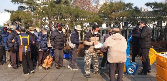 지난 26일 서울시 종로구 탑골공원 담장 옆에서 마스크를 쓴 노인들이 도시락 배식을 받기 위해 밀착해 줄을 서있다.(사진=류태민 기자)