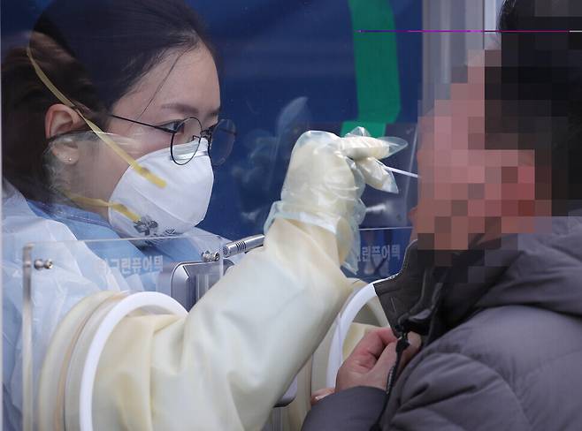 A medical worker takes a sample at a screening center in front of Seoul Express Bus Terminal on Jan. 5. (Yonhap News)