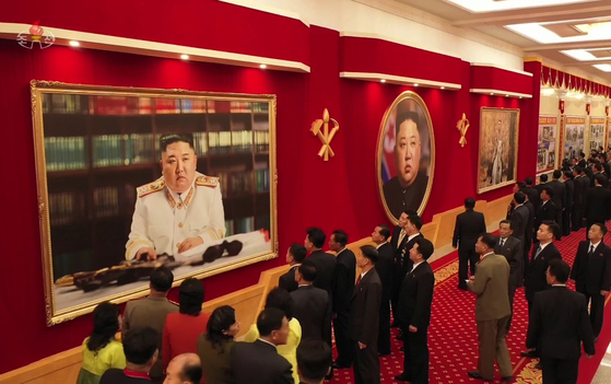 Delegates attending the 8th Congress of the Workers' Party in Pyongyang admire Kim Jong-un's portrait in marshal regalia, as shown in this state media photograph. [YONHAP]