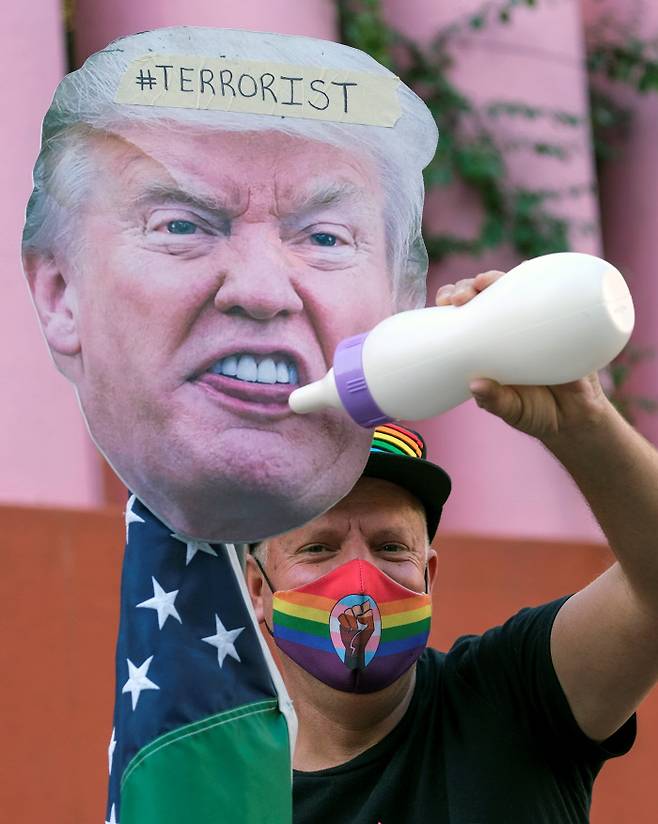 9일(현지시간) 미국 캘리포니아주 로스앤젤레스에서 열린 ‘반트럼프’ 시위에 참가한 한 시민이 도널드 트럼프 미국 대통령의 얼굴 사진에 젖병을 물리는 자세를 취하고 있다.  로스앤젤레스 | 로이터연합뉴스