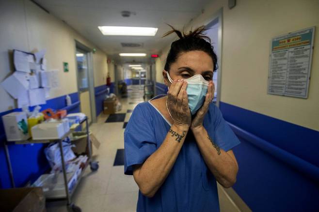 한 간호사가 지난 4월10일 이탈리아 밀란의 한 병원에서 방역 마스크 대신 치과용 마스크 두장을 겹쳐 쓰고 코로나19 환자를 돌보러 가고 있다. AP연합뉴스