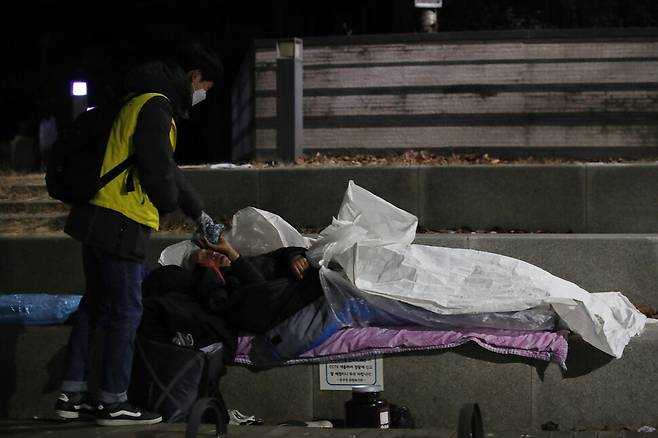 서울시립 다시서기종합지원센터 노숙인 아웃리치 상담원이 10일 밤 서울 중구 서울역 인근 공원에서 거리 노숙인들에게 핫팩, 빵, 마스크 등을 나눠주며 그들의 안부를 묻고 있다. 백소아 기자 thanks@hani.co.kr