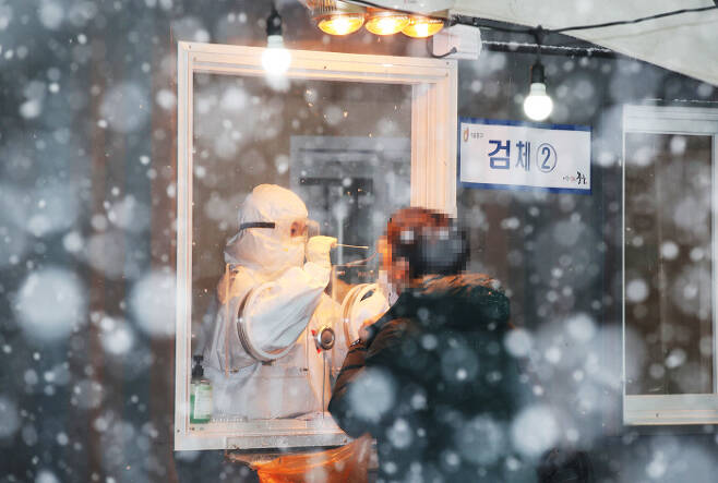 눈이 내린 12일 오후 서울역 광장에 마련된 코로나19 임시 선별검사소에서 시민이 검사를 받고 있다. 연합뉴스