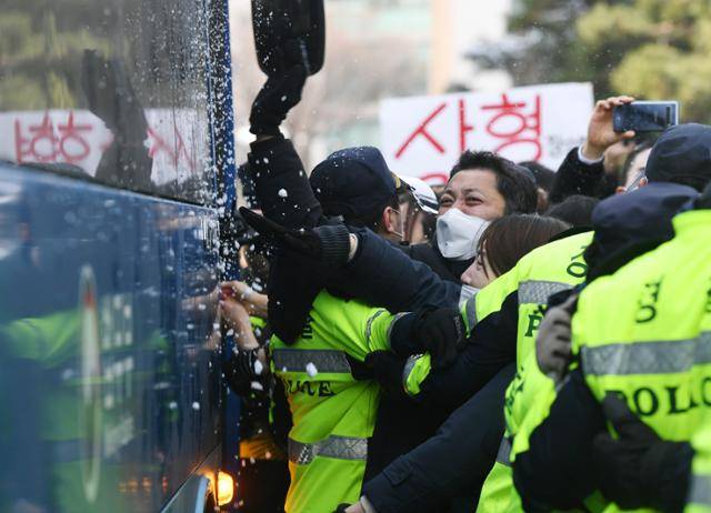 정인양 양부모의 첫 재판이 종료된 13일 서울 양천구 남부지방법원에서 시민들이 양모 장모씨가 탄 것으로 추정되는 호송버스가 나오자 차량을 두들기고 눈을 던지며 분노하고 있다. 고영권 기자