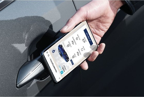 현대 '디지털 키'를 통해 최신 아반떼의 차량 문을 여는 모습. 특정 스마트폰에 대한 홍보를 방지하기 위해 스마트폰 앞면 카메라 부분은 포토샵으로 처리했다. [사진 현대차]