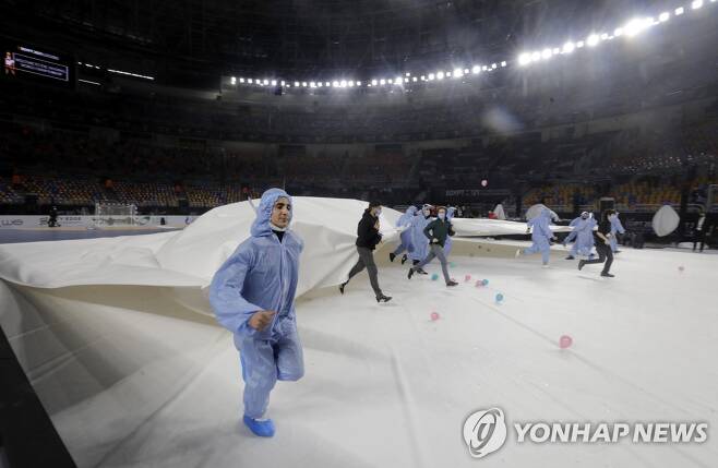 방호복을 입은 경기 진행 요원들이 개막전에 앞서 코트를 정비하는 모습. [로이터=연합뉴스]