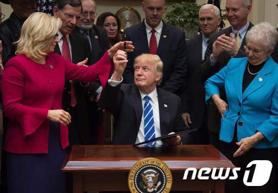 리즈 체니 공화당 하원의원(왼쪽)이 트럼프 대통령에게 펜을 주고 있다. © AFP=뉴스1