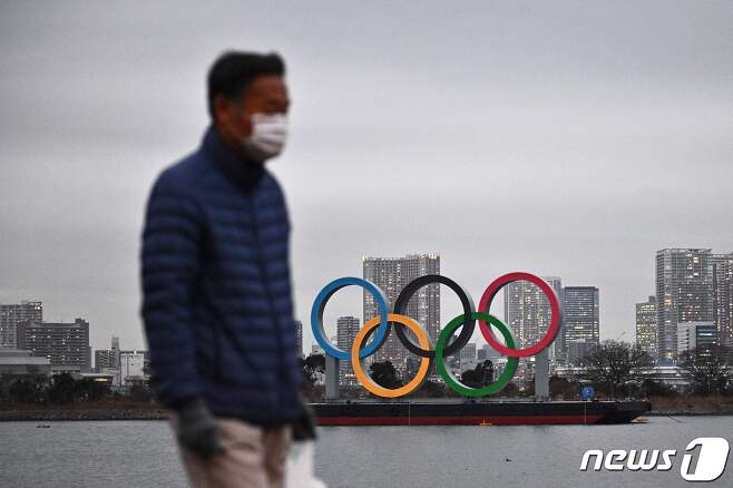 일본 도쿄에서 마스크를 착용한 행인이 올림픽 조형물 앞을 지나고 있다. © AFP=뉴스1