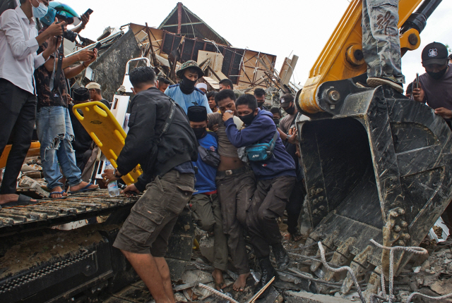 15일(현지 시간) 규모 6.2의 강진이 발생한 인도네시아 술라웨시섬 마무주에서 구급 대원들이 생존자를 구조해 건물 잔해 속을 빠져나오고 있다. 이날 새벽 발생한 지진으로 최소 34명이 숨지고 637명이 부상을 당했다./AP연합뉴스