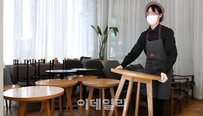 새로운 방역조치 시행을 하루 앞둔 17일 서울 종로구 도렴동 할리스커피 센터포인트점에서 매니저가 그동안 사용하지 못한 테이블과 의자를 정리하고 있다.(사진=이데일리 방인권 기자)