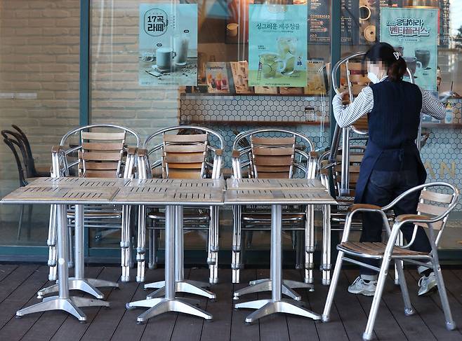 17일 서울 시내 한 카페에서 종업원이 외부 좌석을 정리하고 있다. 18일부터 정부의 새로운 방역조치에 따라 그동안 포장·배달만 허용됐던 카페에서 오후 9시까지 매장에서 취식할 수 있게 된다. 연합뉴스