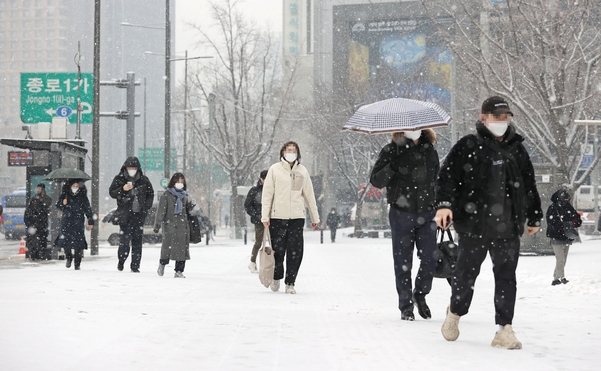 눈이 내리는 18일 오전 서울 광화문광장 인근에서 시민들이 눈을 맞으며 걸어가고 있다. /연합뉴스