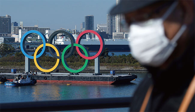 마스크를 쓴 일본인 남성 뒤로 올림픽 상징인 오륜이 보인다. 사진 AP연합