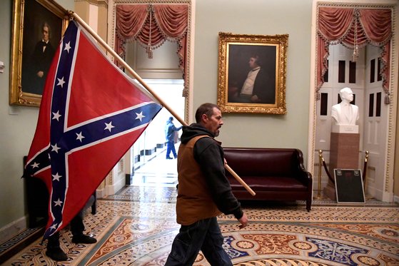 남부연합기를 들고 미 의회에 난입한 한 남성이 찰스 섬너 의원의 초상화 앞을 지나고 있다. [로이터=연합뉴스]