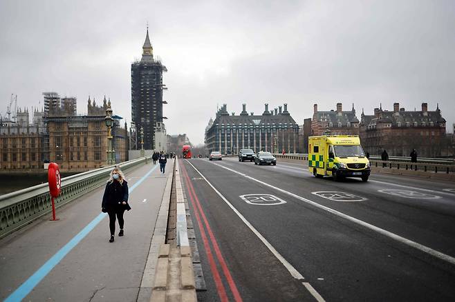 5일(현지 시각) 영국 런던 웨스트민스터 다리. 마스크를 쓴 한 시민이 사람이 없어 휑한 다리를 건너고 있다. /AFP 연합