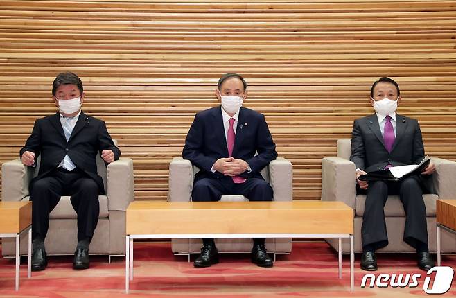 스가 요시히데 일본 총리(가운데)가 22일 오전 각의를 주재하고 있다. 왼쪽은 모테기 도시미쓰 외무상, 오른쪽은 아소 다로 부총리 겸 재무상. © AFP=뉴스1