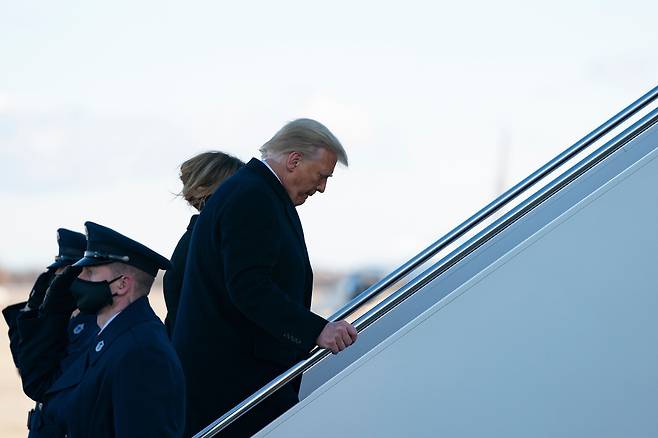 퇴임하는 도널드 트럼프 대통령이 지난 20일(현지시각) 메릴랜드 앤드류스 공군기지에서 플로리다에 있는 자신소유의 마라라고 골프리조트로 가기위해 멜라니아여사와 에어포스원에 오르고있다./AFP 연합뉴스