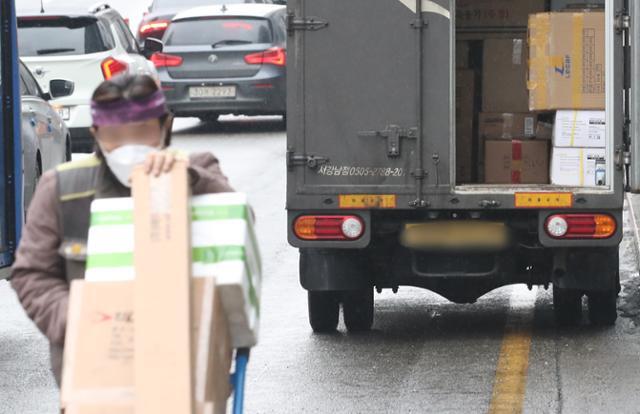 한 택배기사가 21일 서울 시내의 한 도로가에 화물차를 세우고 수북이 쌓인 택배 상자를 옮기고 있다. 뉴스1