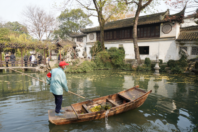 쑤저우 유원에서 관리원이 연못에 떨어진 낙엽을 걷어 올리고 있다.