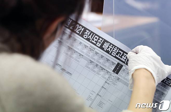 서울 한 학원이 지난달 4일 개최한 2021학년도 대입 설명회에서 한 학부모가 정시모집 배치참고표를 살펴보고 있다./뉴스1 © News1 이재명 기자