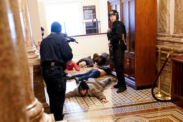 미 의회 경찰이 6일 워싱턴 국회의사당 내 하원 본회의장 인근에서 난입했던 시위대를 붙잡아 총을 겨누며 감시하고 있다. 워싱턴=AP 연합뉴스