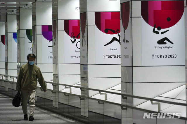 [도쿄=AP/뉴시스]19일 코로나19 예방을 위해 마스크를 쓴 한 남성이 일본 도쿄에서 2020 도쿄 올림픽 현수막 근처를 걷고 있다. 도쿄에서는 이날 1240명의 코로나19 신규 확진자가 보고됐다. 2021.01.19.