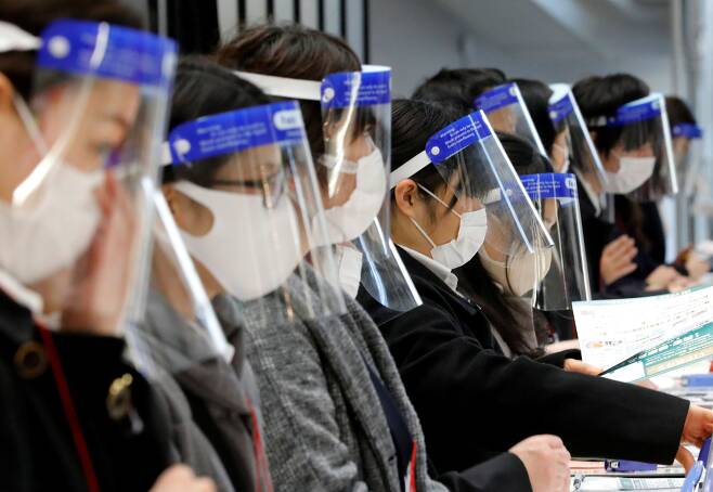 일본 도쿄에서 지난 13일(현지 시각) 전시센터 직원들이 페이스쉴드를 쓰고 리셉션데스크에서 일하고 있다./로이터 연합뉴스