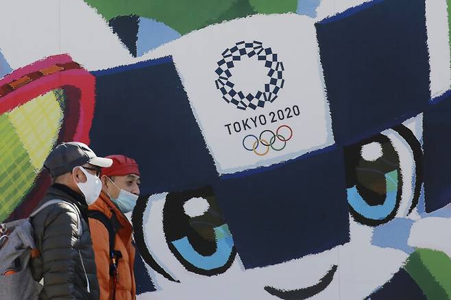 지난 19일 일본 도쿄에서 시민들이 도쿄올림픽·패럴림픽 홍보 포스터 앞을 지나가고 있다. 도쿄/연합뉴스