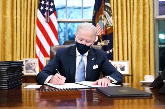 20일(현지시간) 백악관 집무실에서 마스크를 쓰고 업무를 보고있는 조 바이든 미국 대통령 [AFP]