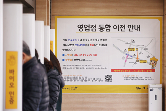 A poster next to ATM machines at KB Kookmin Bank’s branch in Gangdong District, eastern Seoul, on Monday notifies customers that the branch is merging with another nearby branch in Cheonho-dong. With more people opting to use smartphones to conduc their banking business, banks have been closing branches. According to the banking industry, in the first two months of this year, the four leading banks - KB Kookmin, Shinhan, Hana and Woori- will be shutting 26 branches. [YONHAP]