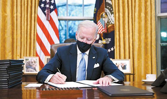 미국의 조 바이든 대통령이 취임 당일인 지난 20일(현지시간) 오후 백악관 집무실에서 마스크를 쓰고 업무를 보고 있다. 1월 20일을 ‘미국 통합의 날’로 지정하는 포고문을 포함, 이날 하루에만 모두 17건의 행정명령·포고문에 서명했다. [AFP=연합뉴스]