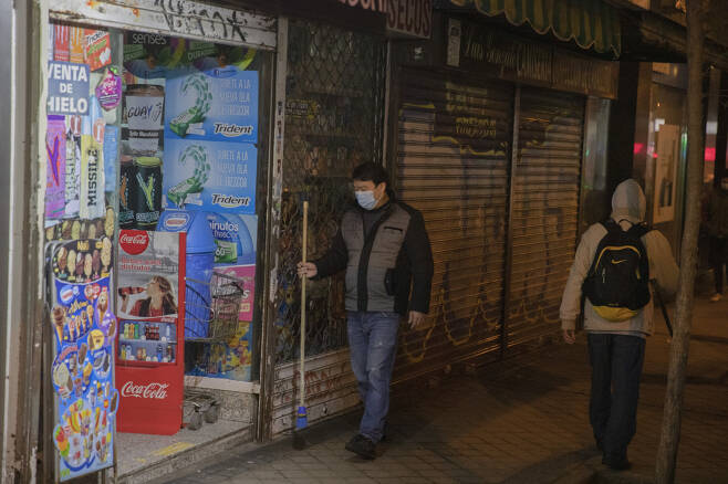 A shop worker prepares to close before the new 10 p.m. curfew comes into effect to control the coronavirus pandemic, in Madrid on Monday. (AP-Yonhap)