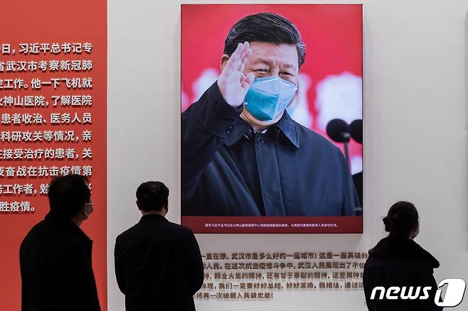 마스크를 착용한 시진핑 중국 국가주석의 대형 사진이 지난 15일 코로나19 최초 발원지인 중국 후베이성 우한시 소재 우한커팅컨벤션센터의 '코로나19 극복' 전시회장에 걸려 있다. © AFP=뉴스1