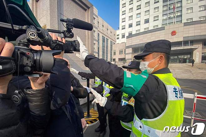 중국 상하이 인민법원 밖에서 한 경찰이 기자들의 영상 녹화를 막기 위해 카메라를 가리고 있다.© AFP=뉴스1