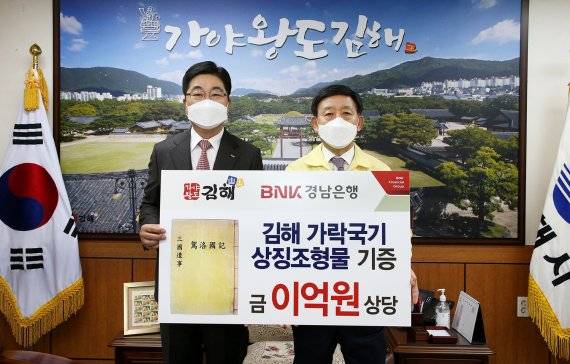 BNK경남은행 황윤철 은행장(왼쪽)이 김해시 허성곤 시장에게 가락국기 상징조형물 기증서를 전달하고 있다. BNK경남은행 제공