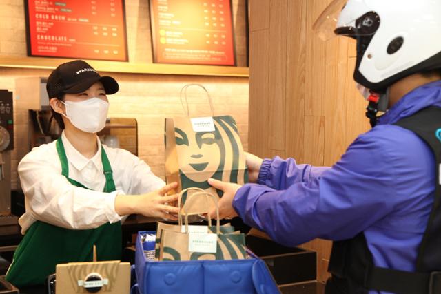서울 강남구 스타벅스 배달 전용 매장에서 직원이 배달대행 업체에 주문 상품을 전달하고 있다. 스타벅스 제공
