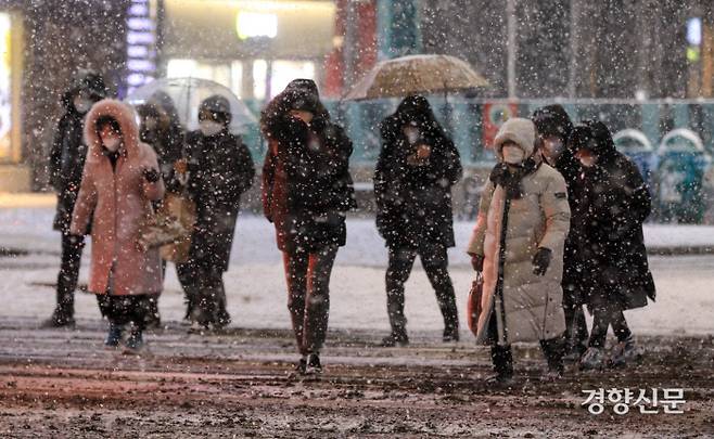 서울 전역에 대설주의보가 발효된 6일  저녁 서울 세종로에서 시민들이 눈을 맞으며 길을 건너고 있다.|우철훈 선임기자