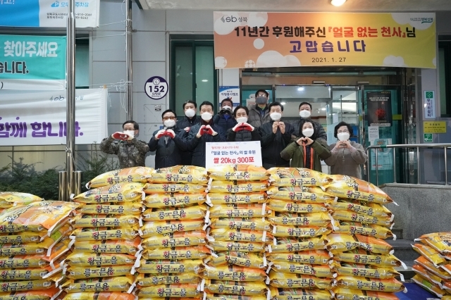 서울 성북구 월계2동 주민센터 직원들이 27일 새벽 전달된 얼굴없는 천사의 쌀 300포를 쌓아두고 기념촬영을 하고 있다. 성북구 제공