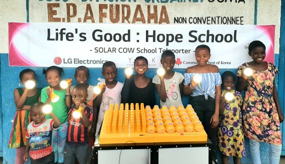 프라하(Furaha) 초등학교 학생들이 LG전자가 설치한 친환경 태양광 충전시스템 '솔라카우'를 이용해 충전한 휴대용 보조 배터리를 사용하며 기뻐하고 있다. LG전자 제공