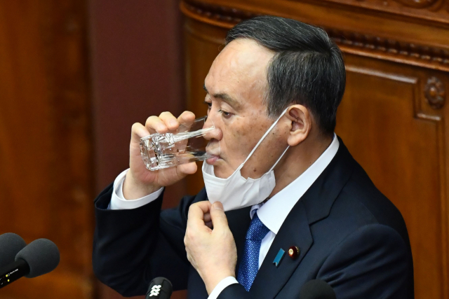 스가 요시히데 일본 총리가 18일 시정방침연설 도중 마스크를 내리고 물을 마시고 있다. /AFP연합뉴스