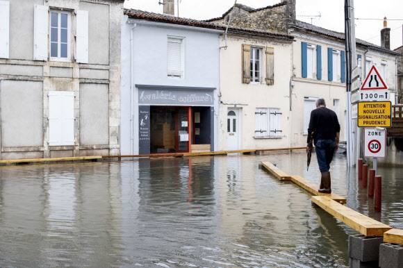 5일(현지시간) 프랑스 남서부 앙굴렘 인근 지역이 홍수로 물에 잠기자 주민이 나무 판자위를 걷고 있다.AP 연합뉴스