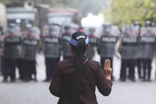 20일(현지시간) 한 여성이 시위대와 대치하고 있는 군경 앞에서 저항의 의미로 세 손가락을 들어 보이고 있다. /AP연합뉴스