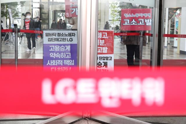 지난달 21일 서울 여의도 LG트윈타워 로비에서 청소노동자들이 '고용 승계'를 촉구하는 손팻말을 들고 집회를 열고 있다. 연합뉴스