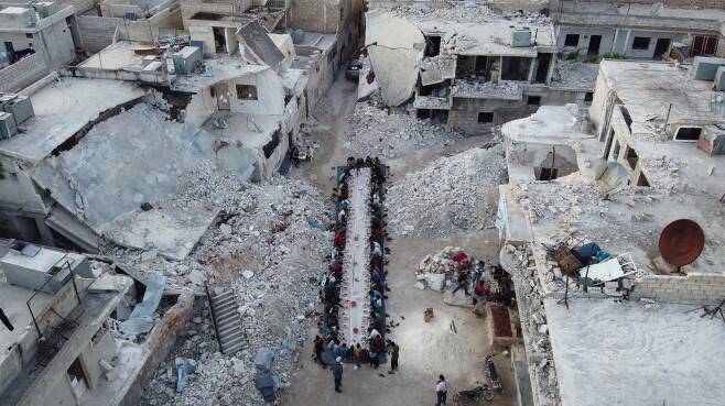 2020년 7월 시리아 알레포 주 아타레브 주민들이 폭격으로 파괴된 마을에서 자선단체의 도움으로 아침 식사를 하고 있다. AFP=연합뉴스