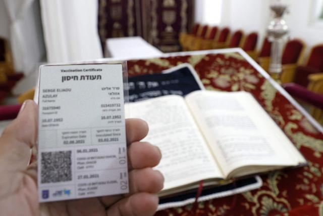 이스라엘의 한 유대교 신자가 지난달 21일 이스라엘 해안 도시 네타냐의 유대교 사원에서 자신의 코로나19 백신 접종증명서 '그린패스'를 보여주고 있다. 네타냐=AFP 연합뉴스