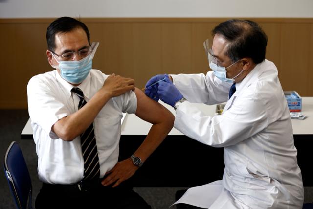 17일 일본의 첫 코로나19 백신 접종자인 아라키 가즈히로(新木一弘) 도쿄의료센터 원장(왼쪽)이 백신을 맞고 있다. 도쿄=AP 뉴시스