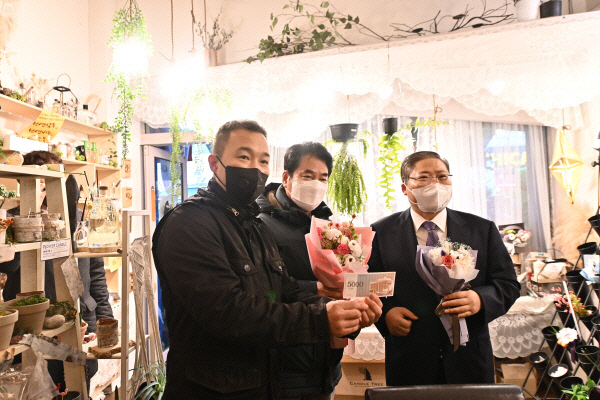 소강석(오른쪽) 목사가 경기 용인시 보정동 카페거리 수에뜨리꽃집을 찾아 윤제후(왼쪽) 대표에게 상품권을 건네고 상품을 구입하고 있다. 가운데는 백군기 용인시장.